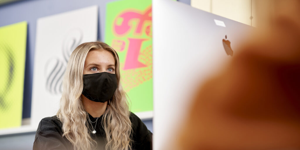 Female student wearing face mask working at computer