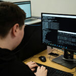 A student sat at a desk typing code into a computer