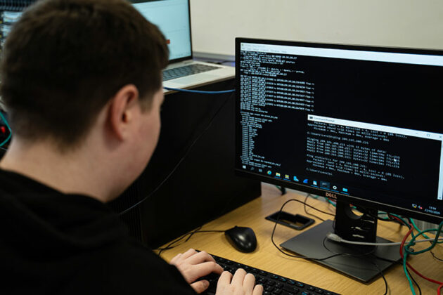 A student sat at a desk typing code into a computer
