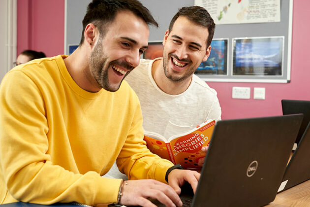 Two male students using laptop