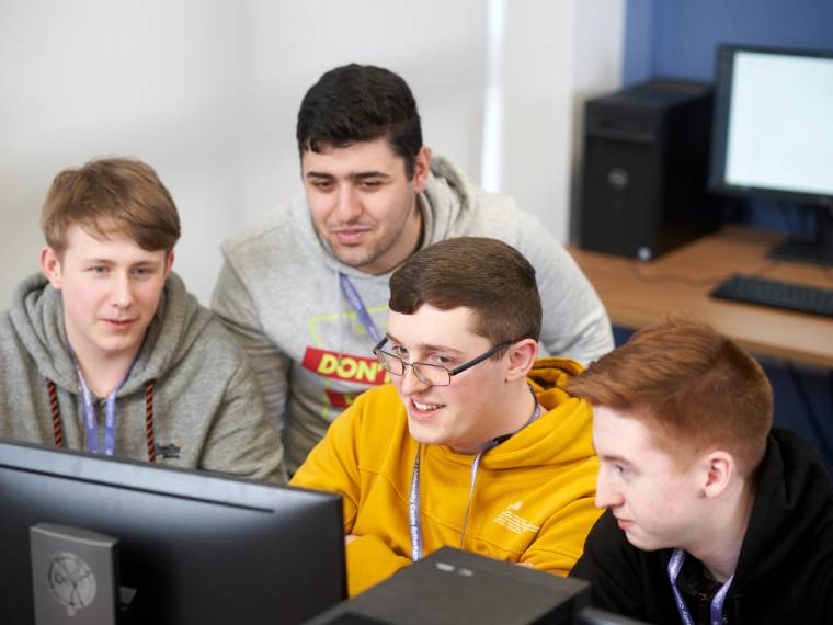 Four students gathered around computer screen